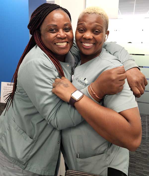 two Capstone Hospice employees smiling and hugging